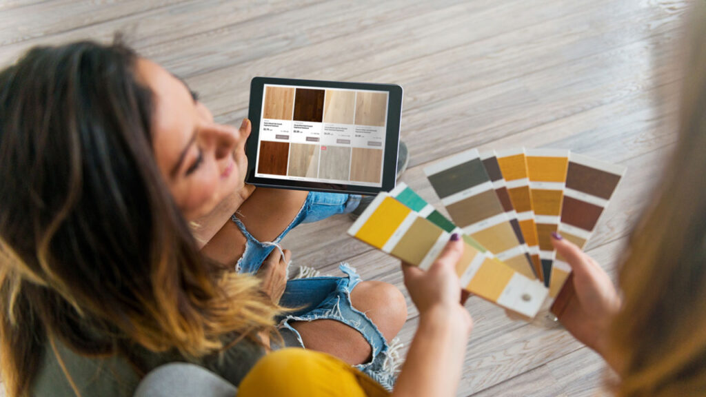 Two women comparing color swatches on a tablet.