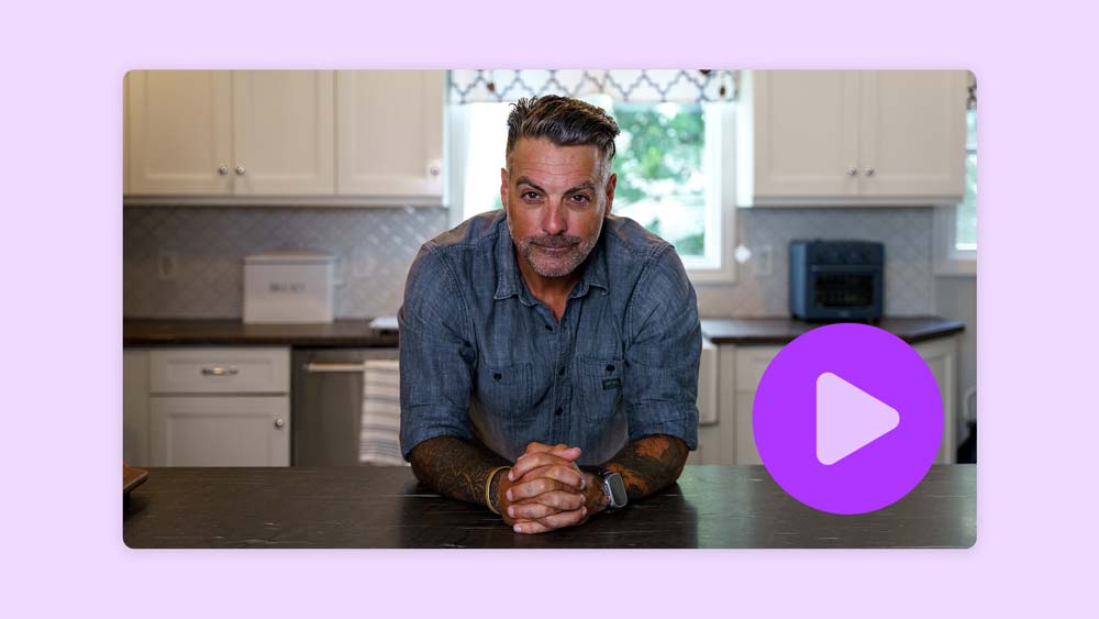 Anthony Carrino leaning on a kitchen island with hands clasped, with a purple play button overlay