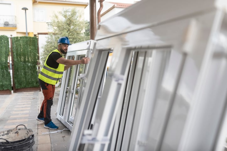 A man is working on installing a window at a construction site.