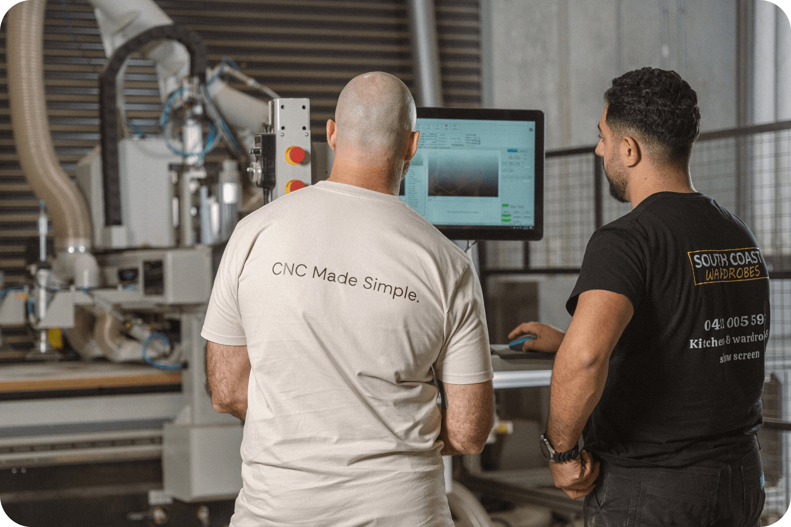 Two men stand in front of an industrial machine