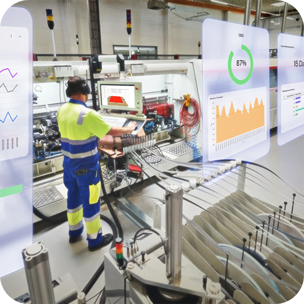 A man is using a laptop while working in a manufacturing facility